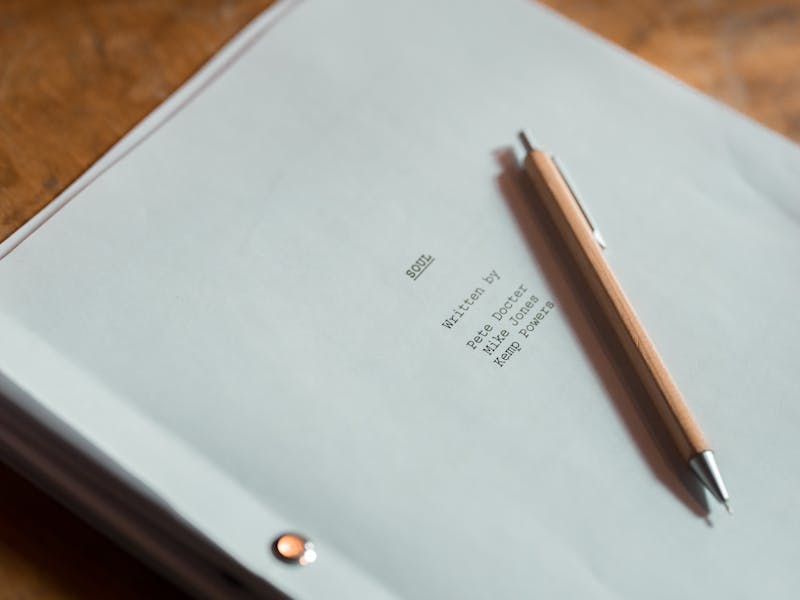 Close-up of a film script titled 'Soul' next to a pen on a wooden desk.