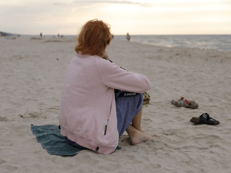 A person sitting on a beach at sunset, capturing a serene and contemplative moment.
